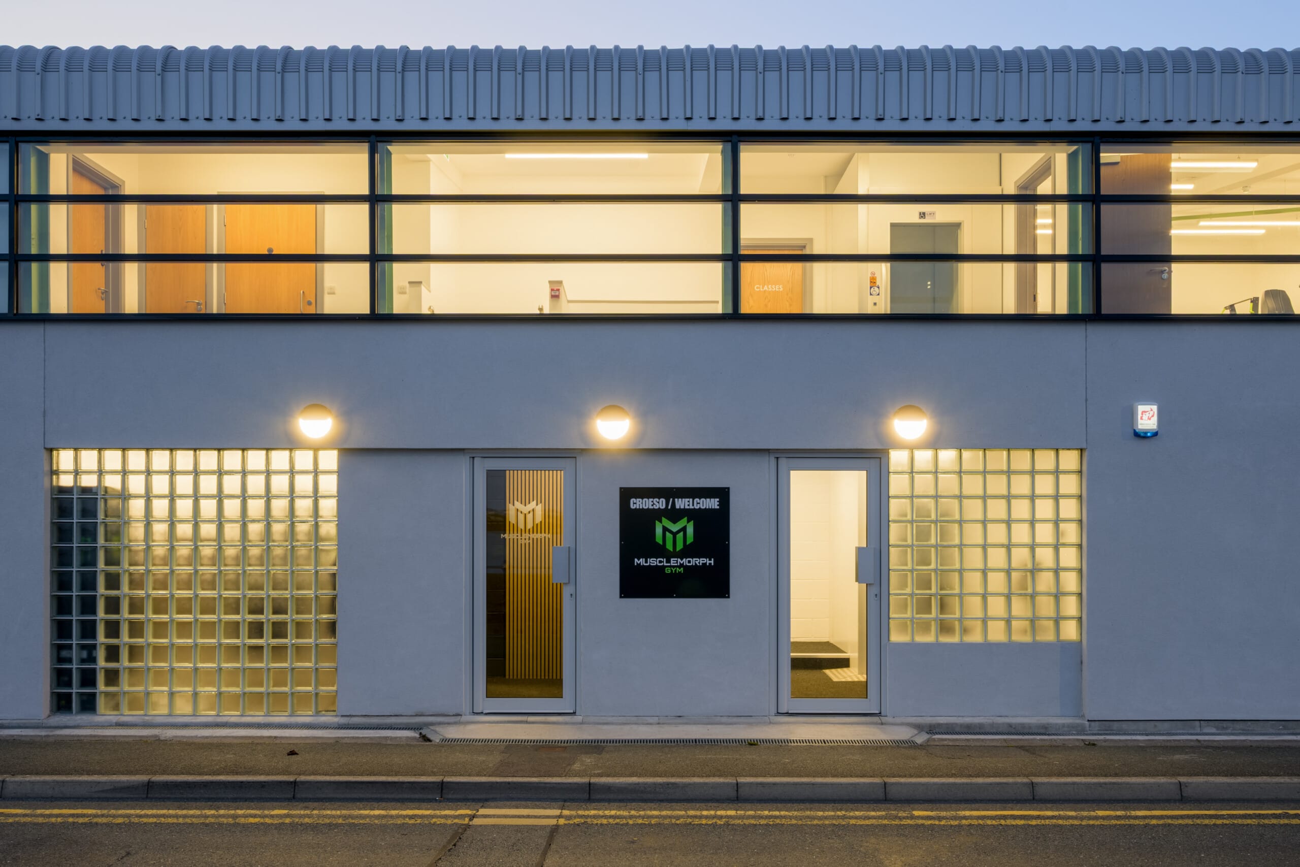 Completed Musclemorph Private Gym retrofit in Pwllheli, showing the illuminated frontage with glass blocks and upper-floor offices