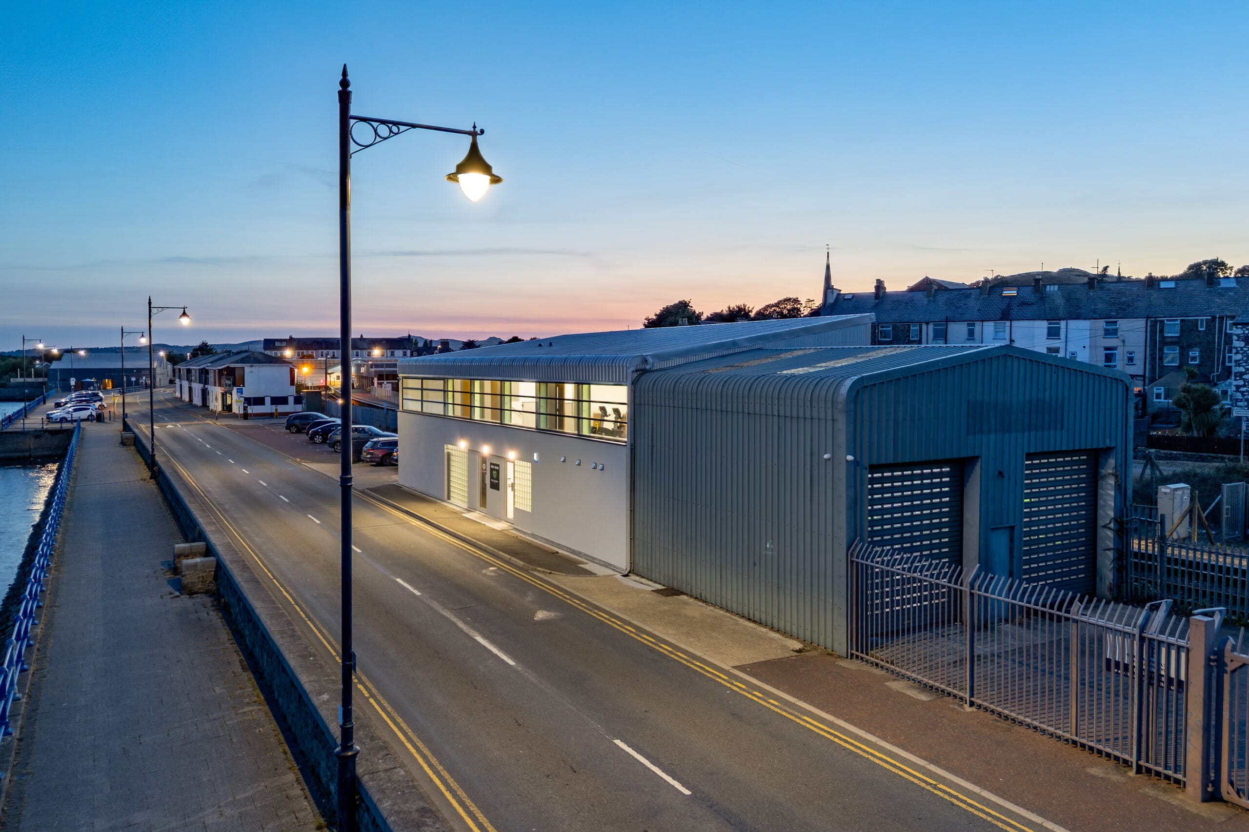 Completed Musclemorph Private Gym retrofit in Pwllheli, showing the side elevation and illuminated harbourfront frontage at dusk